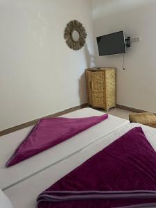 a bedroom with a bed with purple sheets and a flat screen tv at Taghazout surf in Tamraght Ouzdar +1 photo