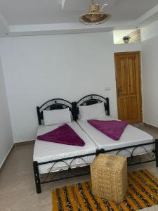 a bedroom with a bed with purple pillows on it at Taghazout surf in Tamraght Ouzdar