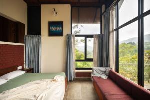 a bedroom with a bed and a large window at Kood Heritage cottages in Vagamon