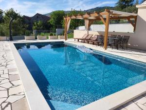 een zwembad met een pergola en blauw water bij Villa Gorana for 10 with large private pool in Sutina