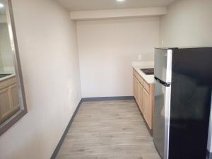 una cucina con frigorifero nero e armadietti in legno di Economy Suites Fort Smith a Fort Smith