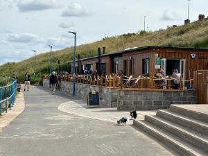 a dog walking on a sidewalk next to a building at Seafront Serenity Lodge in Newbiggin-by-the-Sea