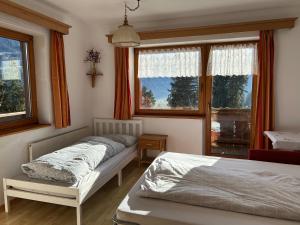 een slaapkamer met twee bedden en twee ramen bij Ferienwohnung Schwendberg in Hippach
