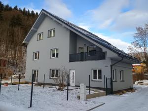 a white house with a balcony in the snow at Apartmán Vail in Svoboda nad Úpou