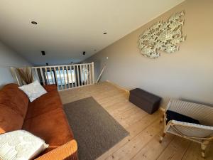 a living room with a brown couch and a wooden floor at Lodges des Pontons - Cap Ouest - vue mer in Saint-Côme-de-Fresné