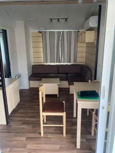 ein kleines Zimmer mit einem Sofa, einem Tisch und Stühlen in der Unterkunft Charmant Mobilhome in Lagrand