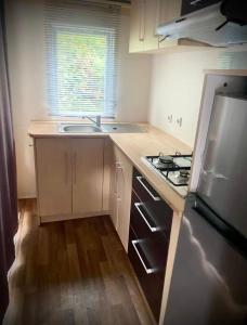 eine kleine Küche mit Spüle und Herd in der Unterkunft Charmant Mobilhome in Lagrand