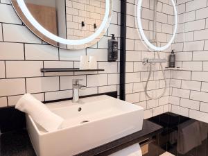 een witte badkamer met een wastafel en 2 spiegels bij Ibis Lunel Petite Camargue in Lunel