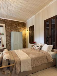 a bedroom with a large bed and a brick wall at Aprosmeno House 7 in Agros