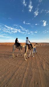 zwei Menschen reiten auf Pferden in der Wüste in der Unterkunft Al Raha Apartments in Badīyah