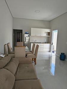 a living room with a couch and chairs and a kitchen at Casa Jardim dourado in Porto Belo