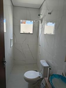 a white bathroom with a toilet and a shower at Casa Jardim dourado in Porto Belo