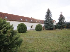 a white building with trees in a yard at Apartment Urlaubszuhause by Interhome in Naundorf