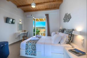 een witte kamer met een bed en een raam bij Lithos Luxury Rooms (Adults Only) in Adamas