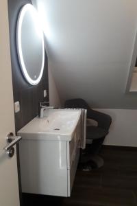 a bathroom with a white sink and a mirror at Apartment Am Wald by Interhome in Westerstede
