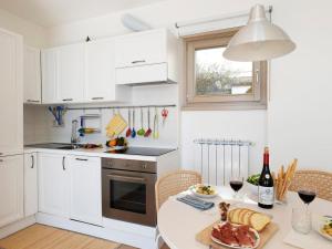 a kitchen with white cabinets and a table with a plate of food at Apartment 'Cezanne by Interhome in Parzanica +13 photos