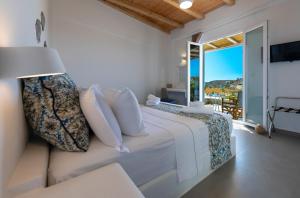 een witte slaapkamer met een bed en een balkon bij Lithos Luxury Rooms (Adults Only) in Adamas +51 foto's