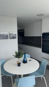 a white kitchen with a white table and blue chairs at Casa Douro in Valbom