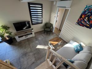 a living room with a couch and a tv at Lodges des Pontons - Cap Sud - vue mer in Saint-Côme-de-Fresné