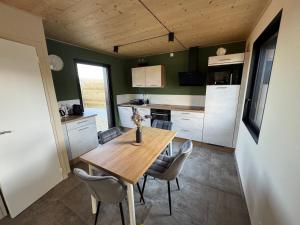 a kitchen and dining room with a wooden table and chairs at Lodges des Pontons - Cap Sud - vue mer in Saint-Côme-de-Fresné