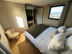 a bedroom with a large bed and a window at Lodges des Pontons - Cap Sud - vue mer in Saint-Côme-de-Fresné