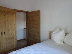 a bedroom with a white bed and a wooden door at Apartment Apartment - Monteure by Interhome in Emmering