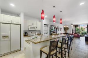 a kitchen with white cabinets and a bar with bar stools at Elegant Condo in High-End Resort Community with Pool and Beach Club Access in Coco