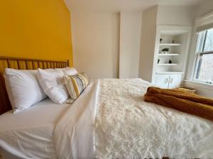 een slaapkamer met een wit bed met kussens en een raam bij Jungle House Columbus Short North Downtown Free Parking - Near Convention Center & Nationwide Arena - 4BR Luxury Home - Sleeps 12 - Over 5,800 Five Star Stays in Columbus +35 foto's