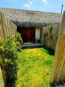 een klein huis met een rieten dak en een tuin bij Suíte privativa 2 com Ar e Frigobar Casa Full Hausi in Fortim