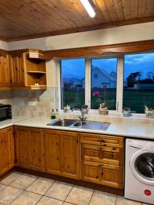 a kitchen with a sink and two windows at Sonnys Rest in Ardara
