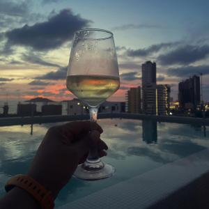 a person holding a glass of wine on a rooftop at Stylish Condo Steps to Beach & Malecón in Mazatlán