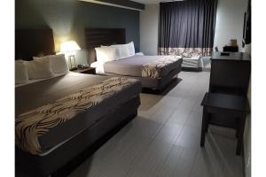 a hotel room with two beds and a desk at Regency Inn & Suites Houston East I 10 in Houston