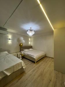 een slaapkamer met 2 bedden en een kroonluchter bij Royal in Osh