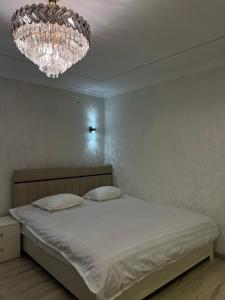 een slaapkamer met een bed en een kroonluchter bij Royal in Osh