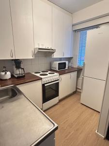 a kitchen with white cabinets and a stove and a refrigerator at Lomayksiö Vääksy 34m2 in Vääksy