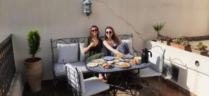 zwei Frauen sitzen an einem Tisch und essen in der Unterkunft Dar Abdesalam in Fès