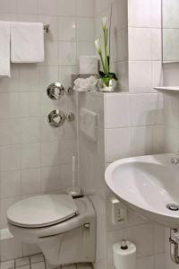 La salle de bains blanche est pourvue de toilettes et d'un lavabo. dans l'établissement Sure Hotel by Best Western Mannheim City, à Mannheim