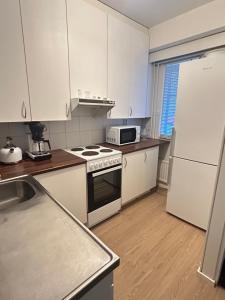 a kitchen with white cabinets and a stove and a refrigerator at Lomayksiö Vääksy 34m2 in Vääksy