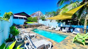 a swimming pool with white chairs and a yellow umbrella at Ruta Verde BB in Tambor