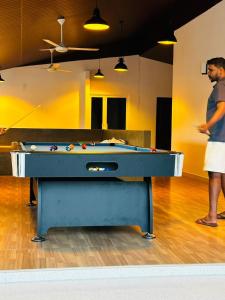 un uomo in piedi di fronte a un tavolo da biliardo di Ceylon Lodge - Airport Transit Hostel a Negombo