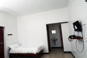 a room with a bed and a tv on a wall at Aroma Resort Hill Palace in Kolli Hills