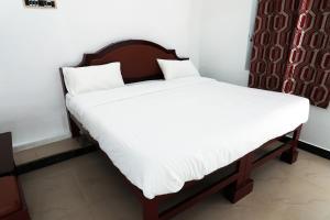 a bed with white sheets and a wooden headboard at Aroma Resort Hill Palace in Kolli Hills +21 photos