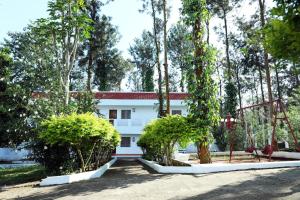 a white building with trees in front of it at Aroma Resort Hill Palace in Kolli Hills