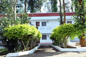 a white building with trees in front of it at Aroma Resort Hill Palace in Kolli Hills