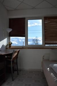 a bedroom with a bed and a desk and two windows at Kaunas Homestay in Kaunas