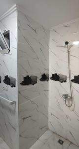 een badkamer met douche en witte marmeren muren bij Listing Room Dual in Oulad Yakoub