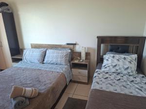 een slaapkamer met twee bedden en een nachtkastje bij Apart próximo a Unimed, Catedral, HSA com 2 Ar e garagem in Santo Ângelo