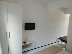a white room with a bed and a tv on a wall at Brisa Brasil Residence in Fortaleza