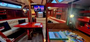 a small room with a red table and a tv at Voilier de tout confort in Cherbourg en Cotentin +45 photos