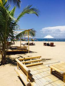 una spiaggia con panchine e tavoli sulla sabbia di Merpati - Studios a Sanur